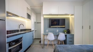 A modern kitchen with a built-in oven, a sink, and a dining area with two chairs and a table. - Oceanfront Studio Campeche Beach Aar0203 (Florianópolis)