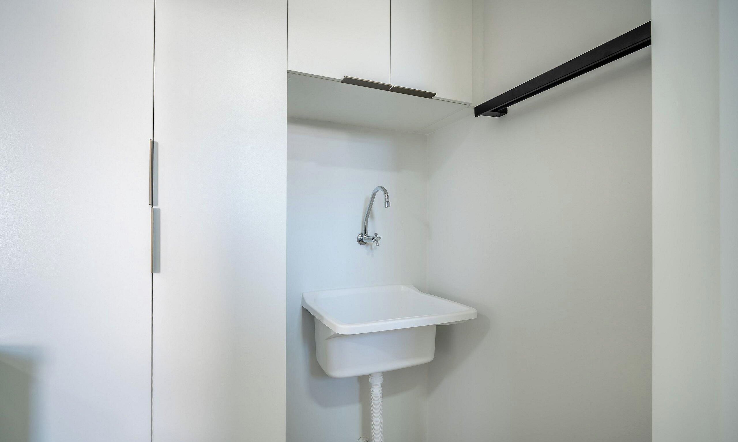 A small, white bathroom with a single sink and a shower.