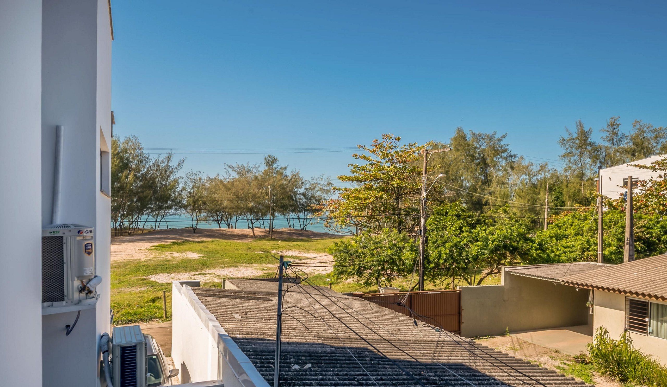 Ett bostadsområde med utsikt över en strand, ett järnvägsspår och en byggnad med en luftkonditioneringsanläggning.