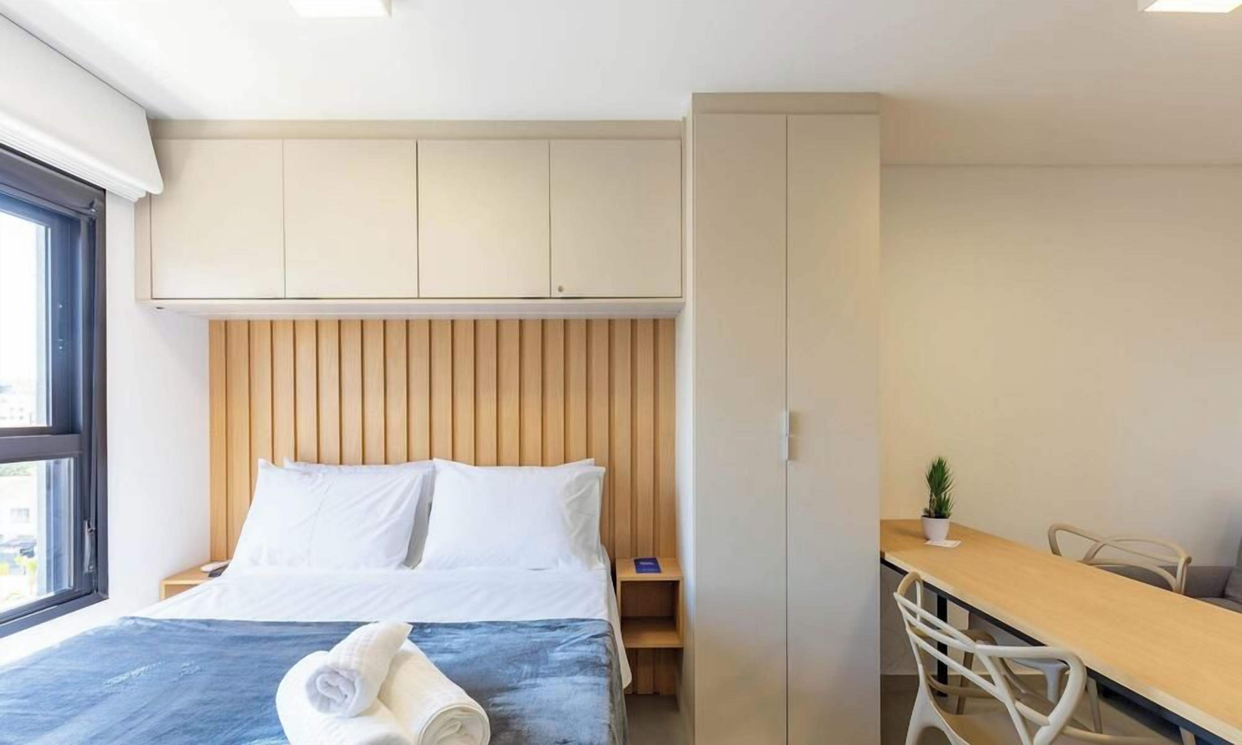 A hotel room with a bed, a desk, and a wardrobe.