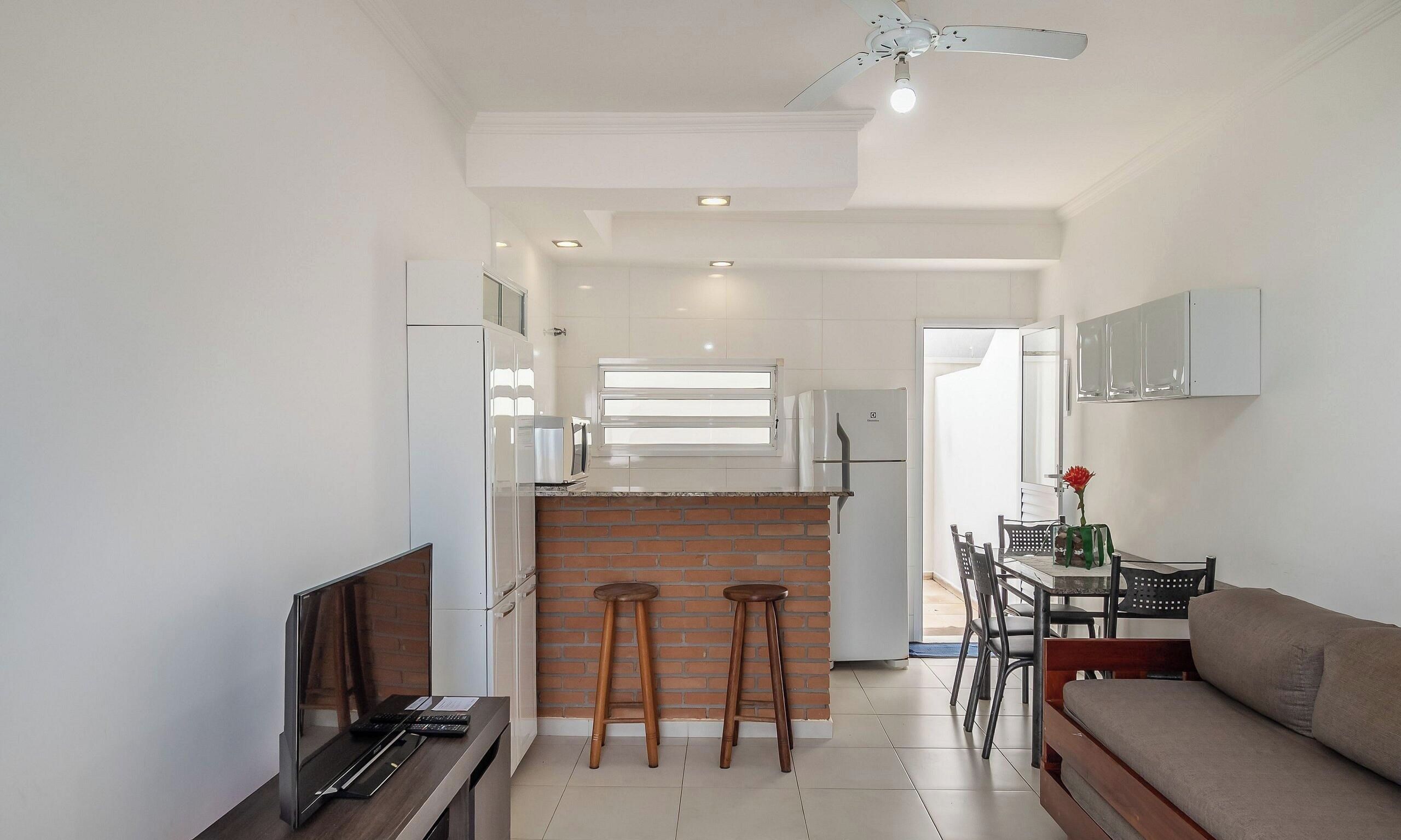 A modern kitchen with a brick accent wall, a dining area with a table and chairs, and a sofa.