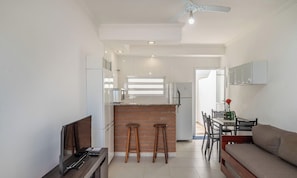 A modern kitchen with a brick accent wall, a dining area with a table and chairs, and a sofa. - Complete apt a few Steps From the Beach - Fua0003 (Ubatuba)