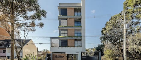 A modern multi-story building with a flat facade, large windows, and a gated entrance.