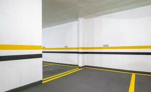 A parking garage with white walls, yellow and black lines, and numbered parking spaces. - Apt in Guarapari Center, 300m From the Sea Eep0602 (Guarapari)