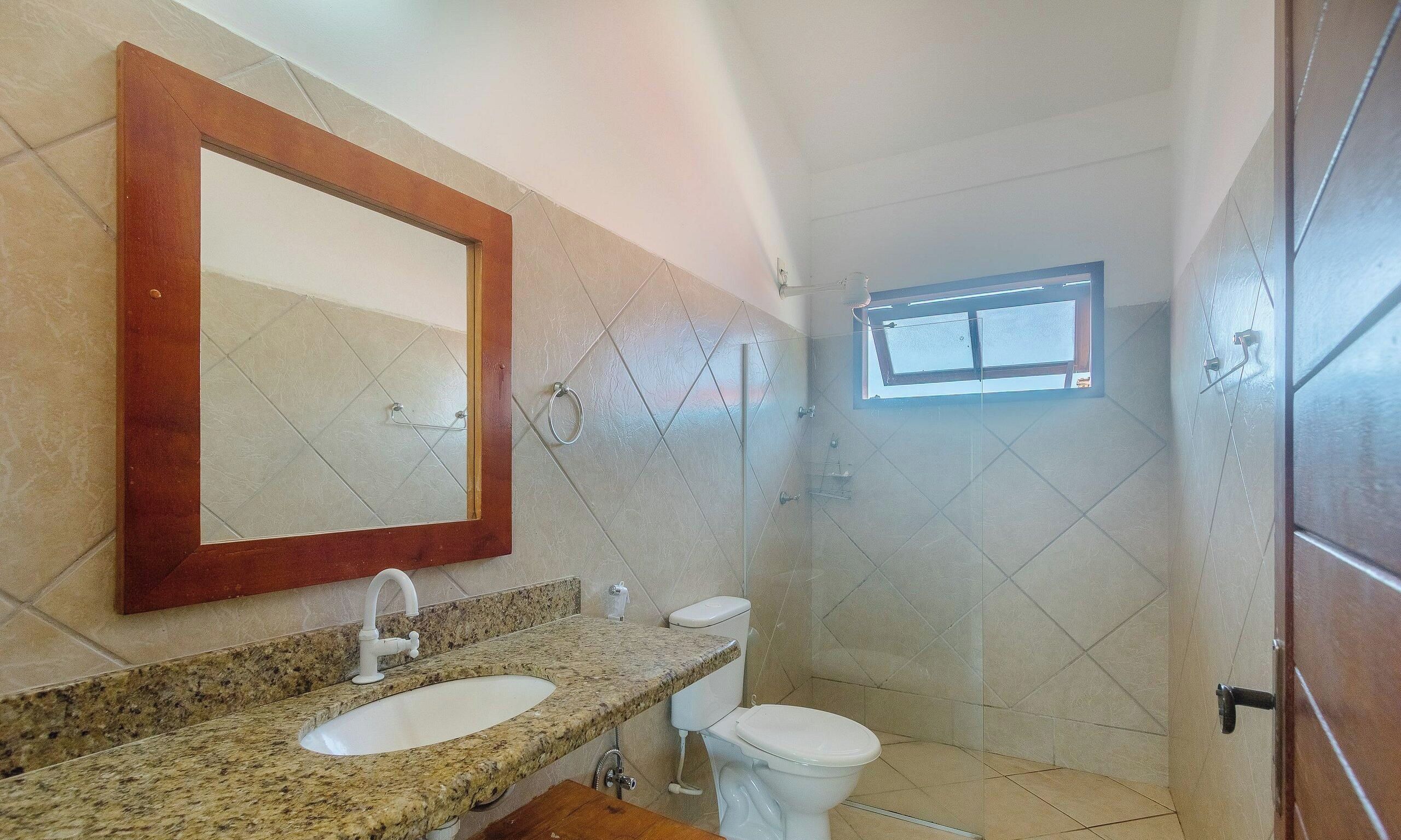 Un baño con un espejo grande, dos lavamanos, un inodoro y una zona de ducha.