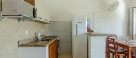A compact kitchen with a microwave, refrigerator, and a dining area with chairs and a table.