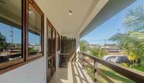 Un balcón con vistas a un paisaje urbano, una valla de madera y una pequeña mesa con una silla.