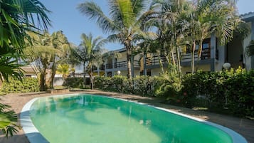 Una piscina rodeada de palmeras y un edificio con balcones.