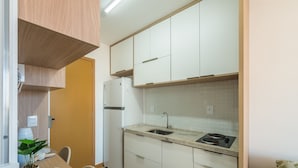 Una cuina compacta amb armaris blancs, un sollloc integrat i una petita superfície de treball.
