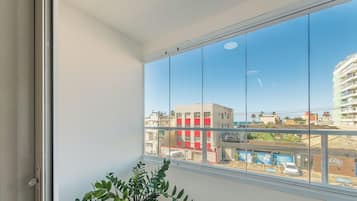 Una habitación con un ventanal que ofrece vistas a un paisaje urbano, una planta en maceta y una puerta.