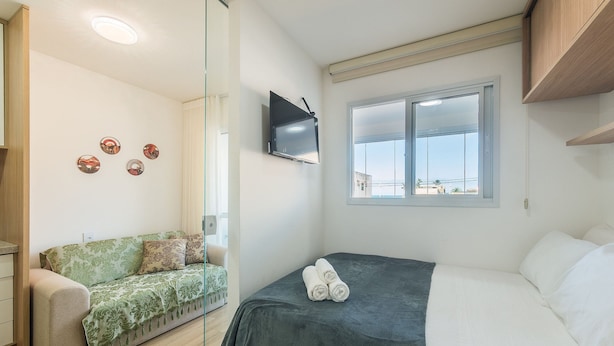 Habitació amb llit, sofà, televisió i finestra amb vista.