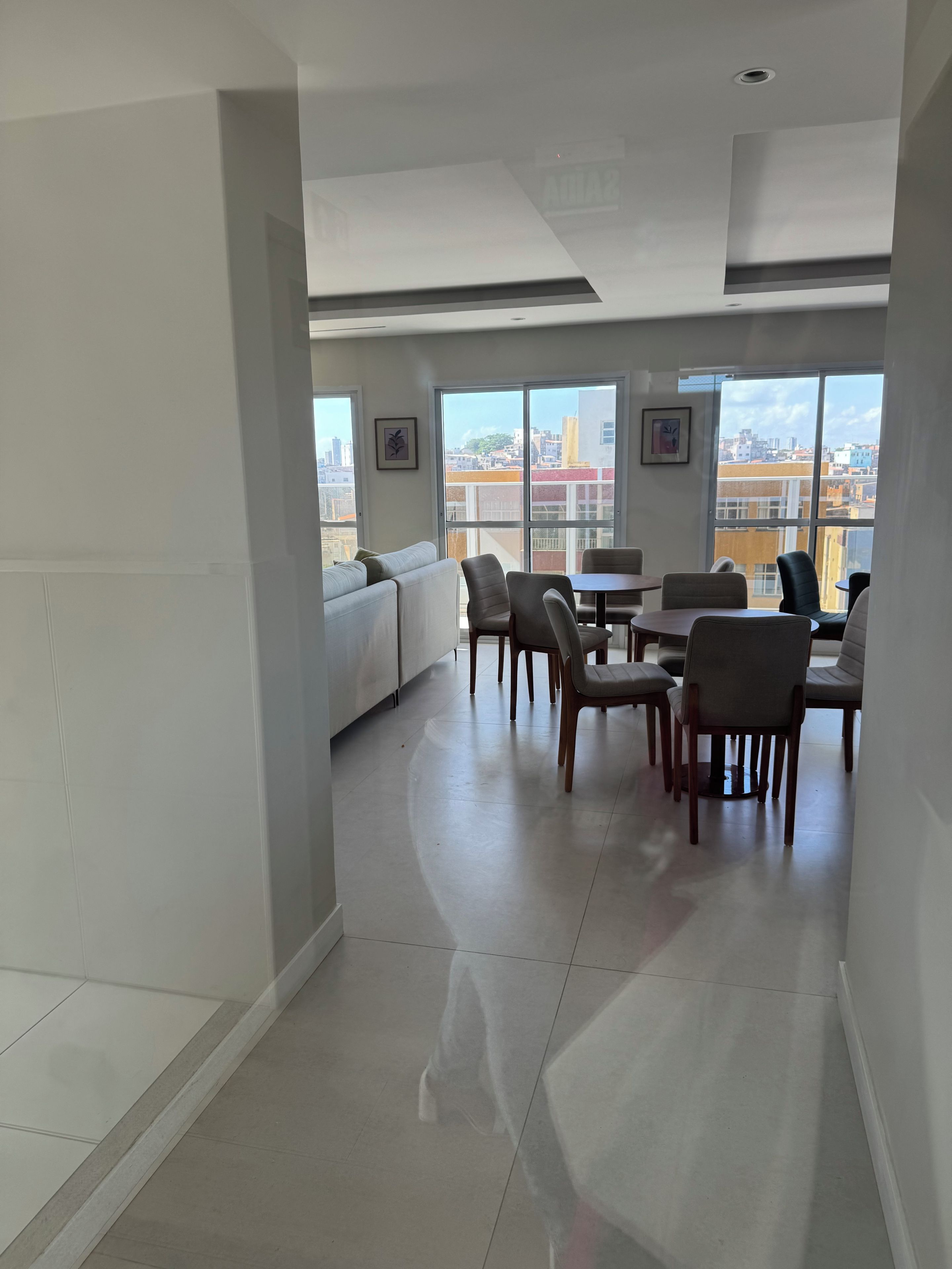 Una habitación amplia con zona de comedor, ventanas grandes y vistas a la ciudad.