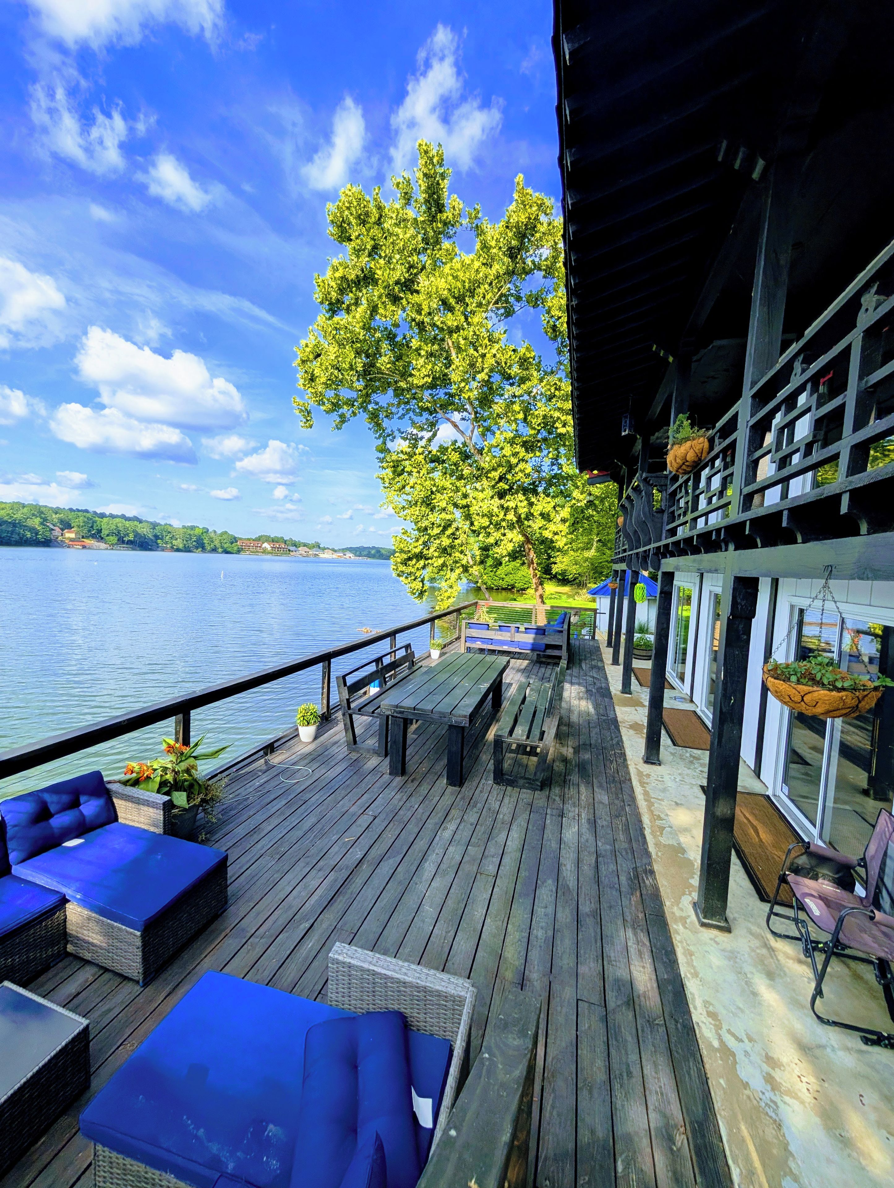 Une terrasse en bois avec des sièges extérieurs, donnant sur une étendue d’eau.