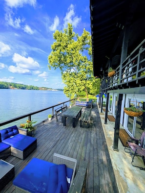 Une terrasse en bois avec des sièges extérieurs, donnant sur une étendue d’eau.