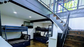 Quarto com vários níveis, beliches, escada e piso de madeira.