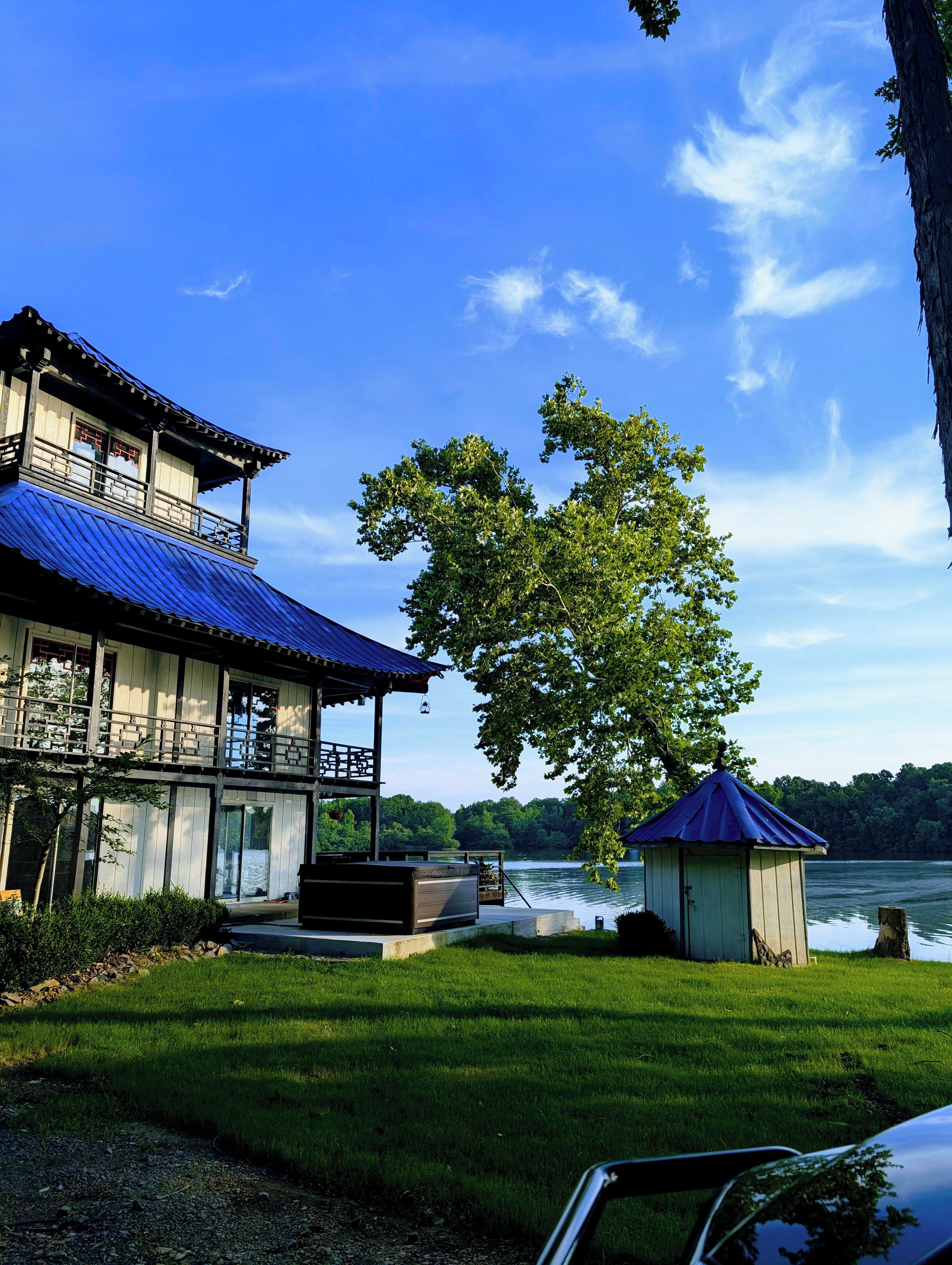 Un bâtiment traditionnel avec un toit bleu, une terrasse en bois et une vue sur un lac.