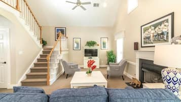 Un salon avec un escalier, une cheminée et un téléviseur.