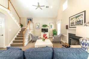 A living room with a staircase, a fireplace, and a television.