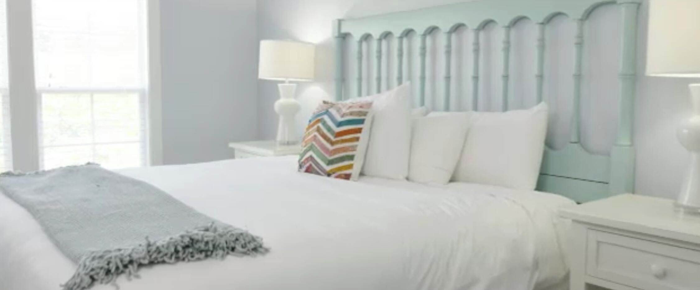 Une chambre d’hôtel avec un lit, une table de chevet, une lampe et une fenêtre.