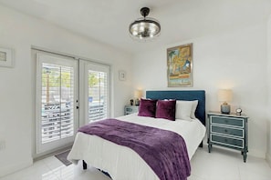 Ein Schlafzimmer mit einem Bett, einem Nachttisch, einem Deckenventilator und einem Gemälde an der Wand.