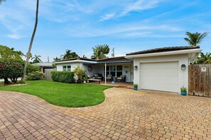 Ein Wohnhaus mit befestigter Auffahrt, überdachtem Patio und einer weißen Garage.