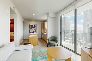 A modern hotel room with a balcony, a sofa, a round table, and a view of the cityscape. - Luxe in the Sky - Skyline Views (Miami)