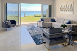 Un salon moderne doté d’une grande porte-fenêtre coulissante donnant sur un balcon avec vue sur la mer.