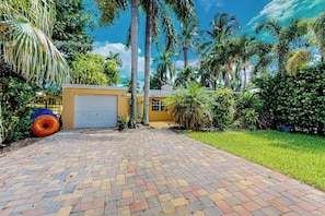 A paved driveway leading to a garage, surrounded by lush greenery and palm trees. - Go with the Flow - Pet Friendly (Hollywood)