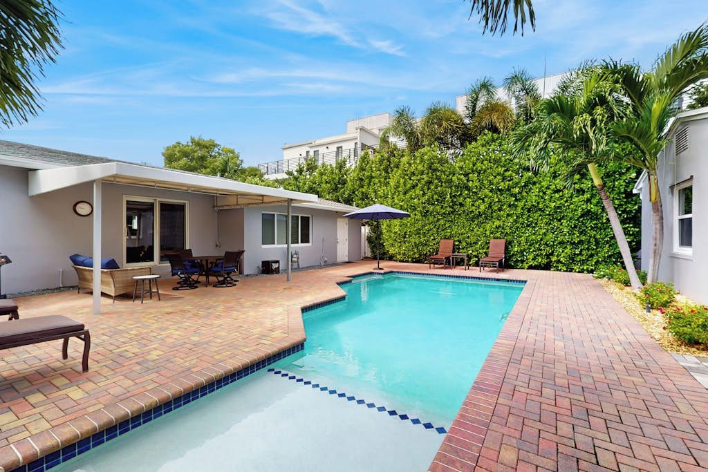 Une piscine dont le bord est revêtu de carrelage, entourée d’une terrasse aménagée avec du mobilier d’extérieur.