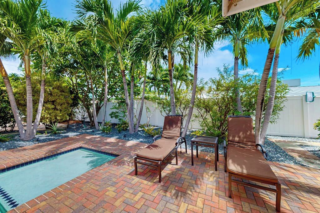 A poolside area with two lounge chairs, a small table, and a tiled pool.