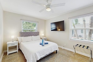 A bedroom with a bed, nightstands, a ceiling fan, a TV, and a window with blinds. - The Cottage - Private Pool (Fort Lauderdale)
