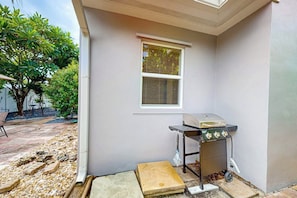 A patio area with a grill, a window, and a small table. - The Cottage - Private Pool (Fort Lauderdale)