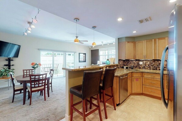 A modern kitchen with a central island, wooden cabinets, and a built-in refrigerator. - Paradise Perch - Intercoastal views (Fort Lauderdale)