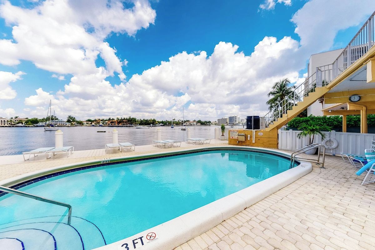 Una piscina con vistas al agua y edificios al fondo.