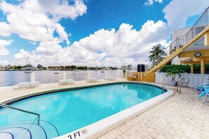 En swimmingpool med udsigt over vandet og bygninger i baggrunden.