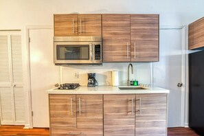 A compact kitchen with a built-in microwave, a coffee maker, and a sink. - So South Beach - Waterfront Condo (Miami Beach)