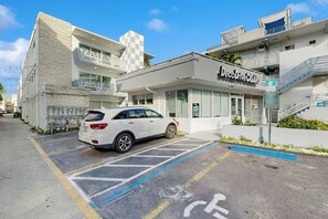 A modern building with a DecoDrive Cigars store, a white car parked in a designated parking space, and a clear blue sky. - Sunshine, Beach & Smiles on Ocean Drive (Miami Beach)