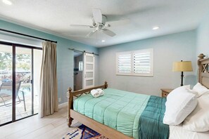 A bedroom with a bed, a ceiling fan, a window with blinds, a nightstand, and a lamp. - Middle River Lookout (Fort Lauderdale)