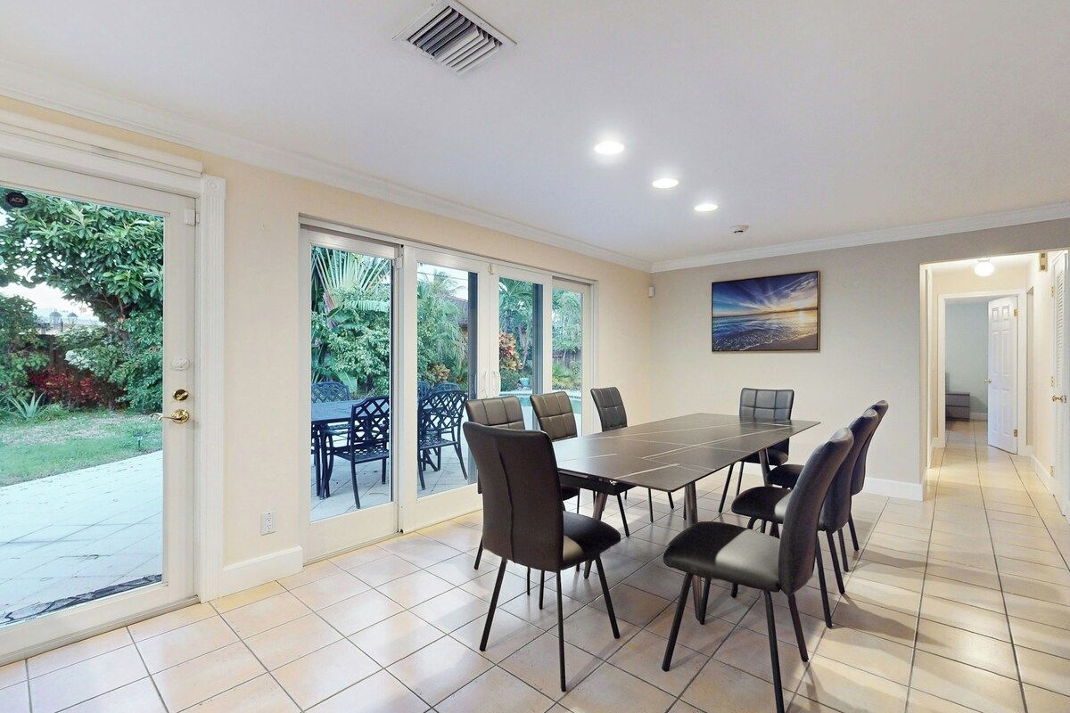 Un espace repas comprenant une grande table et des chaises, de grandes fenêtres et une vue sur l’extérieur.