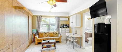 A compact living space with a kitchenette, a dining area, and a sofa.