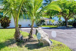 A residential property with a sign indicating a vacation rental, a paved driveway, and a well-maintained lawn. - Coconut Grove Singer Island - Unit 1 (Riviera Beach)
