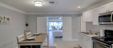 Une cuisine moderne avec des meubles blancs, un four à micro-ondes, une cuisinière et un coin repas comprenant une table et des chaises.