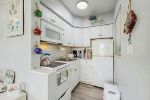 A compact kitchen with white cabinets, a microwave, a kettle, and a refrigerator. - Aloha Beach Holiday - Waterfront (Pompano Beach)