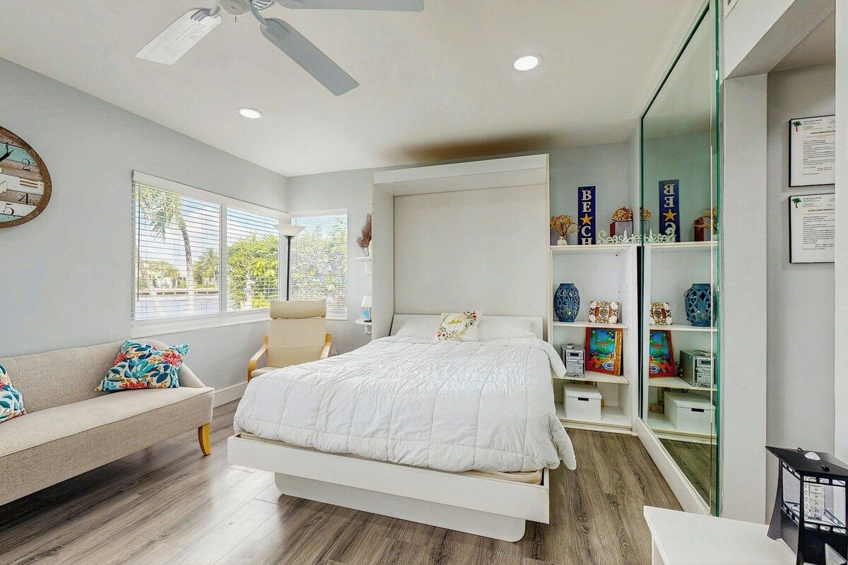 A bedroom with a bed, a bench, a desk, and a bookshelf.