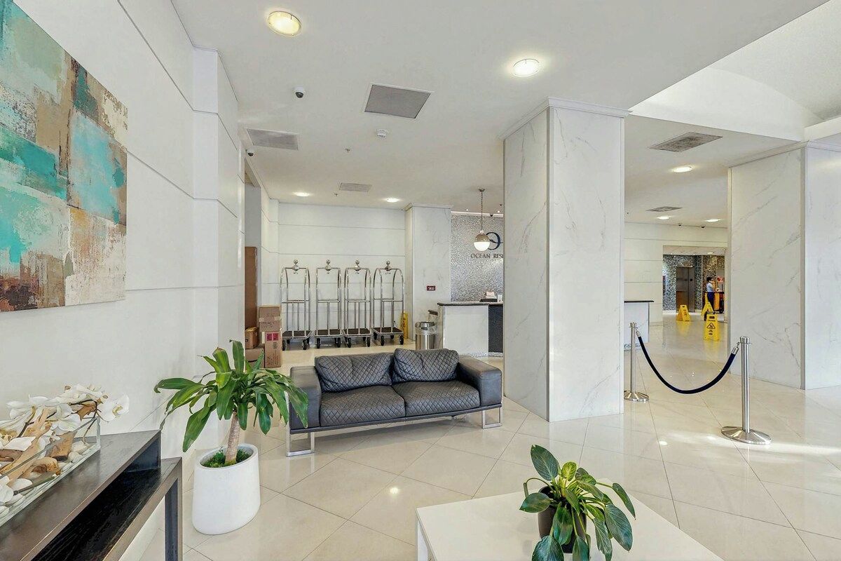 Eine moderne Hotelhalle mit einer Rezeption, einer Couch und Topfpflanzen.