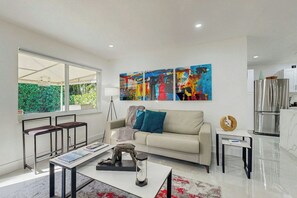 A modern living room with a sofa, coffee table, and artwork on the wall. - 2 BR Home with Private Patio & Grill (Wilton Manors)