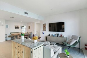 A modern living room with a kitchen area, a dining table, and a seating arrangement. - The Grand Vista 4501 (Miami)