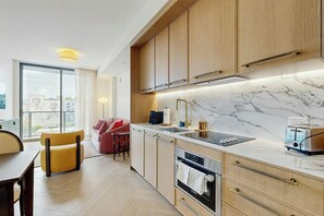 A modern kitchen with wooden cabinets, a marble countertop, and a built-in oven. - NoMad #715 - Private Balcony (Miami)