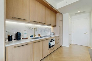 Eine moderne Küche mit Holzschränken, einer Marmorarbeitsplatte und einem eingebauten Backofen.