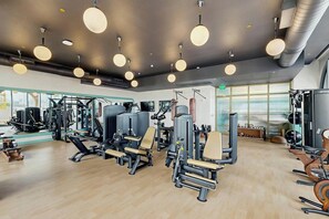A gym with various exercise equipment, large windows, and a modern ceiling design. - NoMad #715 - Private Balcony (Miami)